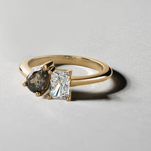 Load image into Gallery viewer, Unique engagement ring in 18K yellow gold, featuring a 0.72ct princess cut lab diamond and a 0.85ct pear-shaped salt &amp; pepper diamond, embodying a blend of classic and unconventional beauty.
