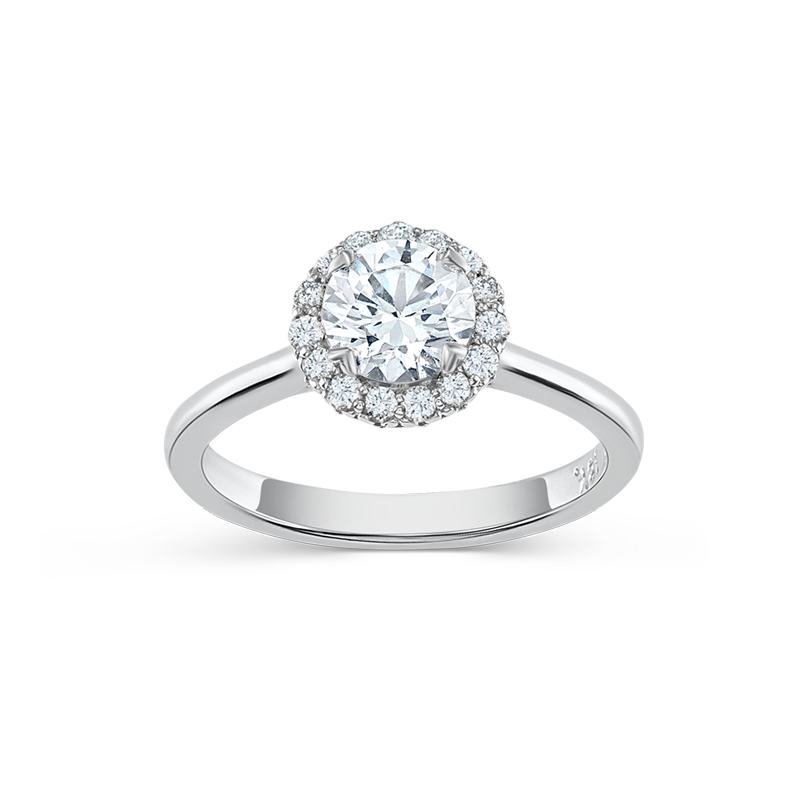 Elegant engagement ring in 18K white gold, featuring a 0.85ct round brilliant center diamond encircled by 0.19tcw smaller diamonds in a bead set halo, with a tulip-inspired decorative gallery and four fancy tipped prongs.