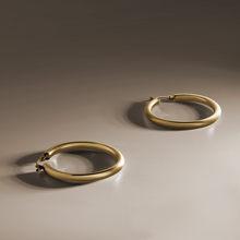 Load image into Gallery viewer, Classic Italian 18K yellow gold hoop earrings, 31mm in diameter with 3mm round tubes, featuring a curved tension post for secure wear, combining all-day comfort with a glossy, impactful look.
