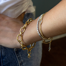 Load image into Gallery viewer, Model wearing an assortment of bracelets, including the Blaze Bangle and yellow gold chains.
