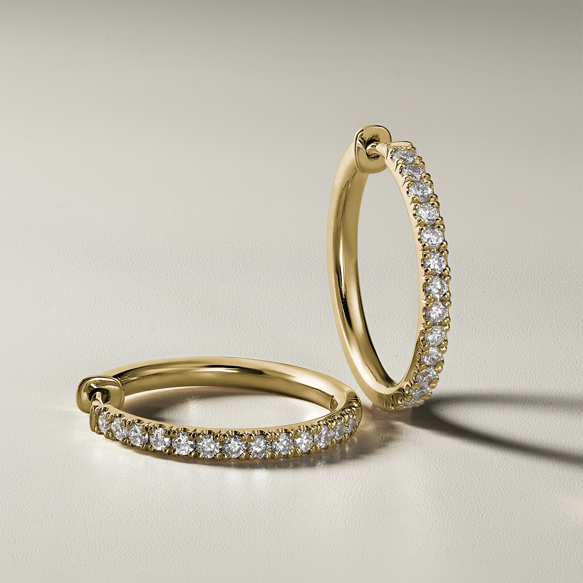 Stylish 18K yellow gold huggers, measuring 18mm in diameter and 2mm wide, featuring a solid strip of pavé diamonds totaling 0.42ct along the front, designed for comfort and reversible wear, handcrafted with love and attention to detail.