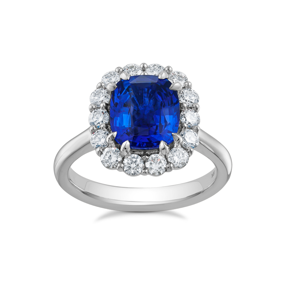 Stunning engagement ring in 18K white gold, featuring a vibrant cushion-cut Ceylon sapphire, surrounded by 14 round brilliant diamonds totaling 0.70tcw, with double eagle claw settings, handcrafted in Montreal by Exaurum.