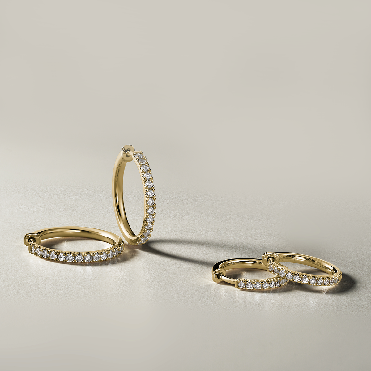 Stylish 18K yellow gold huggers, measuring 18mm in diameter and 2mm wide, featuring a solid strip of pavé diamonds totaling 0.42ct along the front, designed for comfort and reversible wear, handcrafted with love and attention to detail.