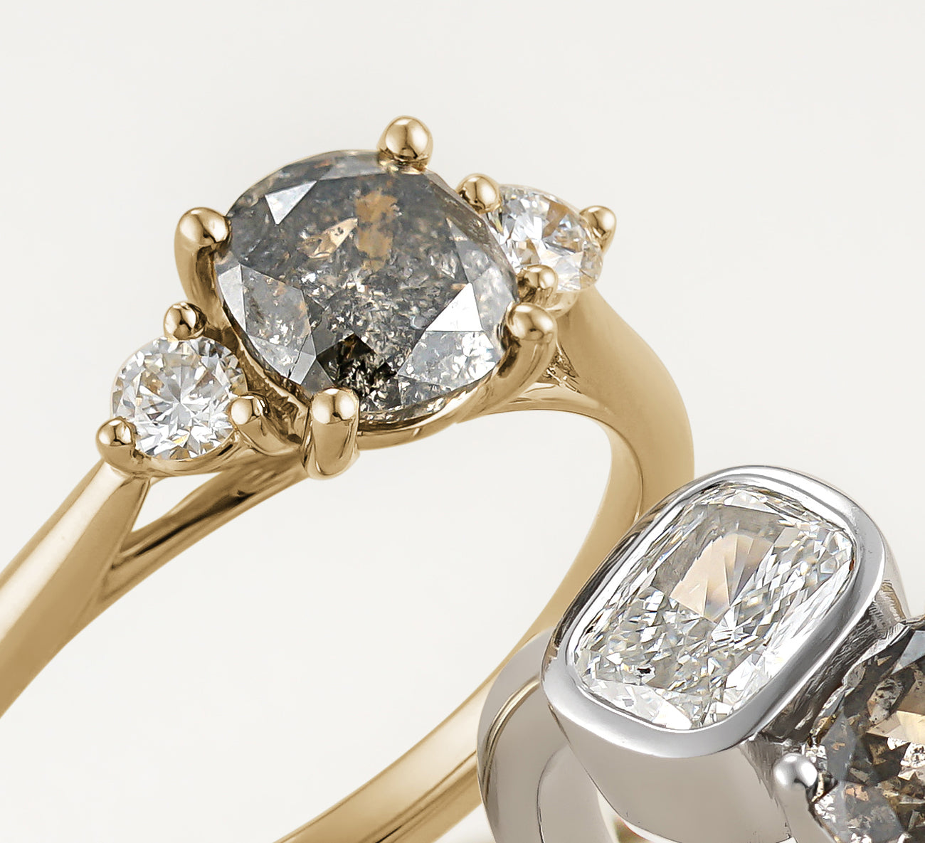 Elegant engagement ring in 18K yellow gold, featuring a 0.94ct oval salt & pepper diamond, flanked by two round brilliant diamonds totaling 0.15tcw, combining tradition with a luxurious warm appeal.