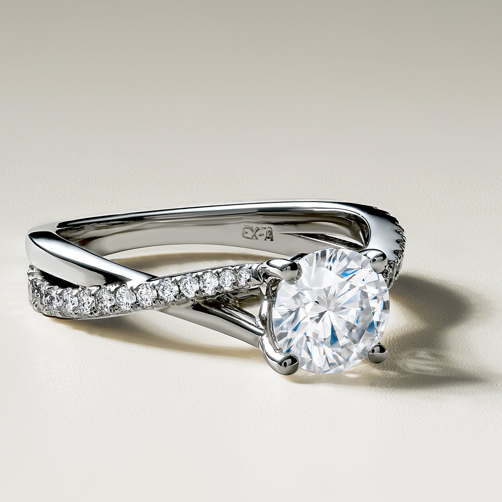 18K white gold ring featuring a 1ct round brilliant center diamond with 0.27tcw of smaller pavé set diamonds in an asymmetrical, sweeping design, symbolizing a serene and continuous motion.