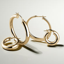 Load image into Gallery viewer, Elegant 10K yellow gold hoop earrings, 25mm in diameter with a 5mm tube width, featuring a high polished glossy finish, offering a luxurious and warm appearance, Italian-made for refined comfort.
