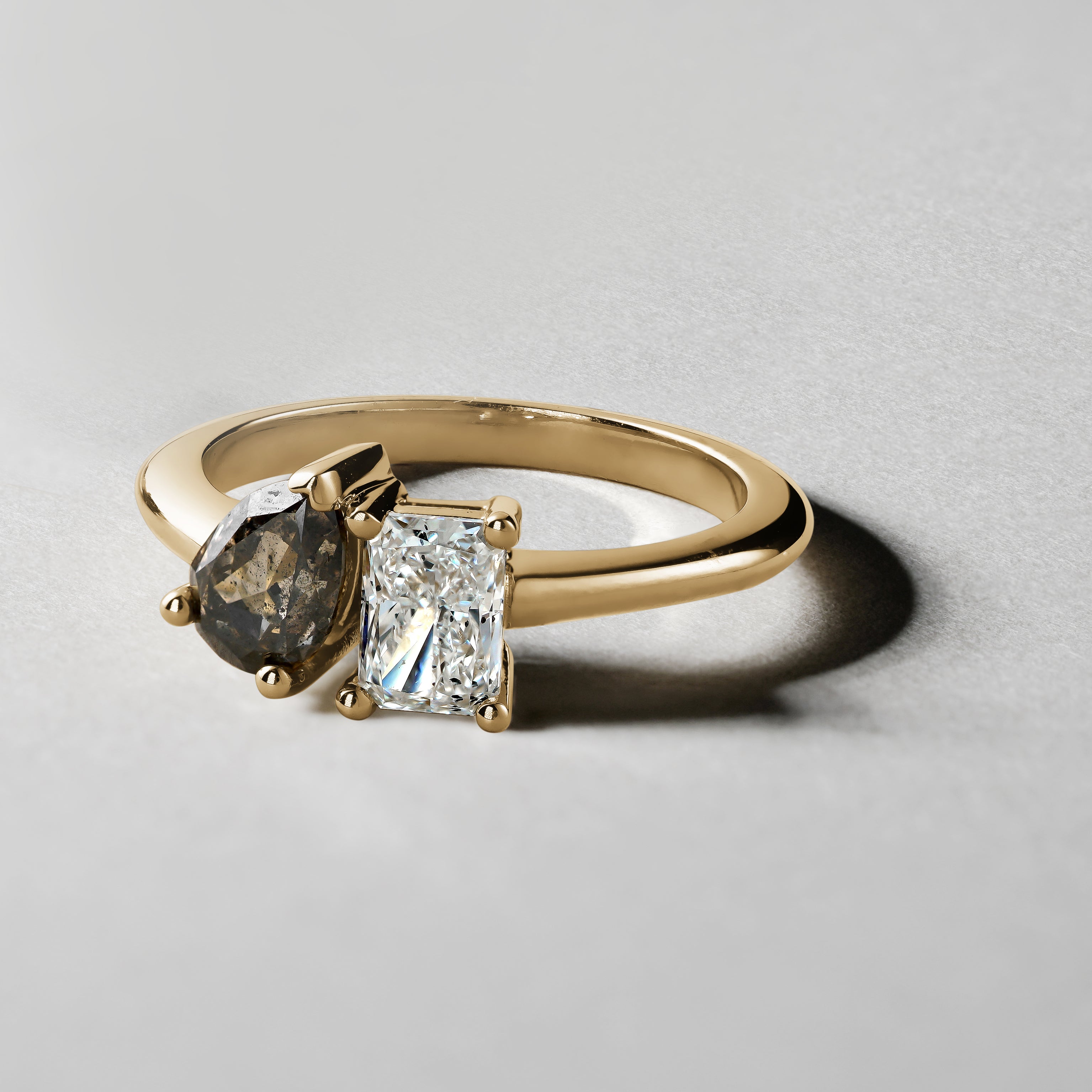 Unique engagement ring in 18K yellow gold, featuring a 0.72ct princess cut lab diamond and a 0.85ct pear-shaped salt & pepper diamond, embodying a blend of classic and unconventional beauty.