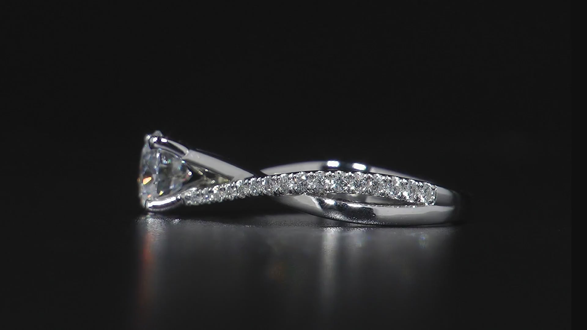 Video showing every angle of our Entwine ring. 18K white gold ring featuring a 1ct round brilliant center diamond with 0.27tcw of smaller pavé set diamonds in an asymmetrical, sweeping design, symbolizing a serene and continuous motion.