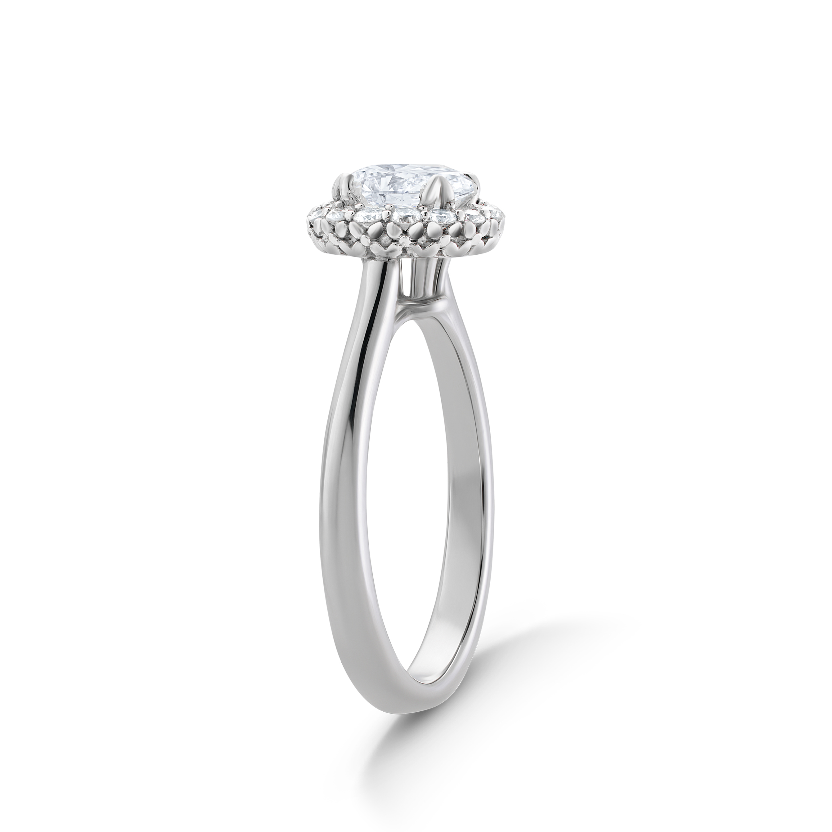 Elegant engagement ring in 18K white gold, featuring a 0.85ct round brilliant center diamond encircled by 0.19tcw smaller diamonds in a bead set halo, with a tulip-inspired decorative gallery and four fancy tipped prongs.