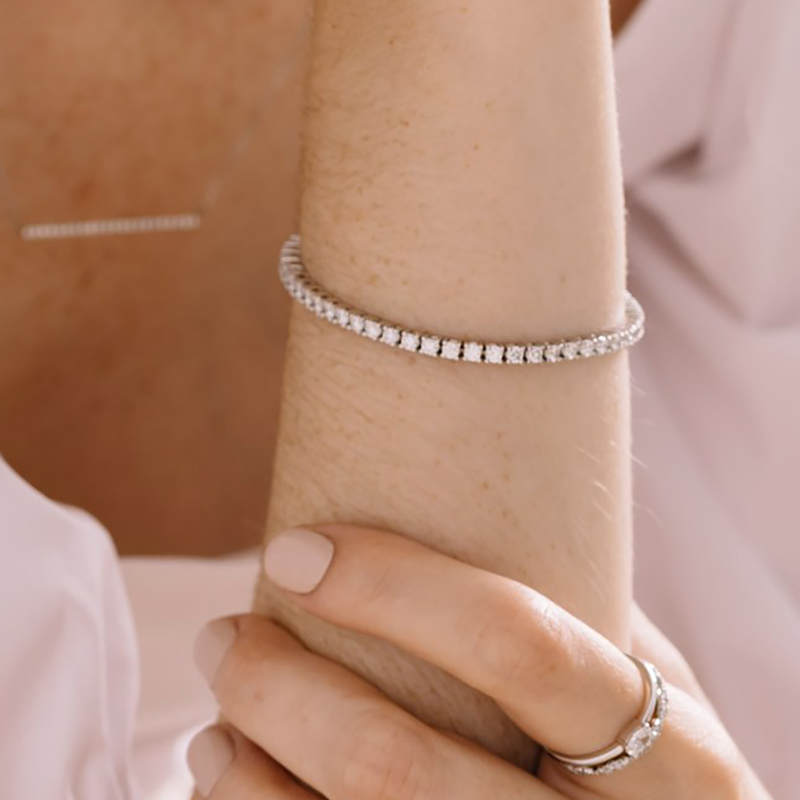Model wearing a luxurious 18K white gold bracelet featuring approximately 4.48ct total weight in claw-set round brilliant diamonds, with a seamless box clasp and double safety clip, measuring about 7 inches in length, crafted by Ex Aurum in Montreal.