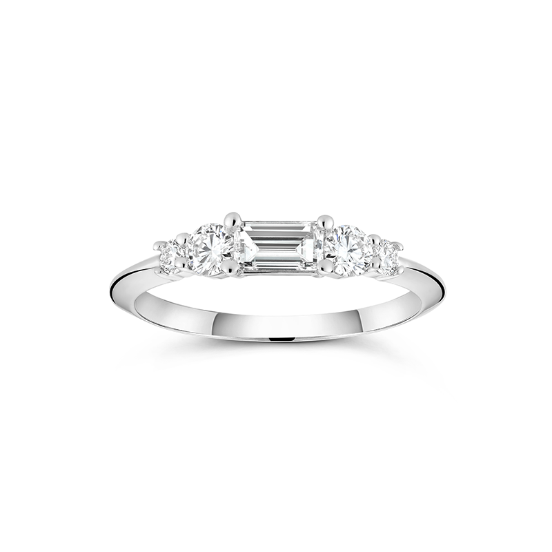 White gold engagement ring with a distinctive low knife-edged band, featuring a 0.31ct baguette cut diamond center, flanked by four round brilliant diamonds totaling 0.58tcw in prong settings, creating a scaffold-like structure.