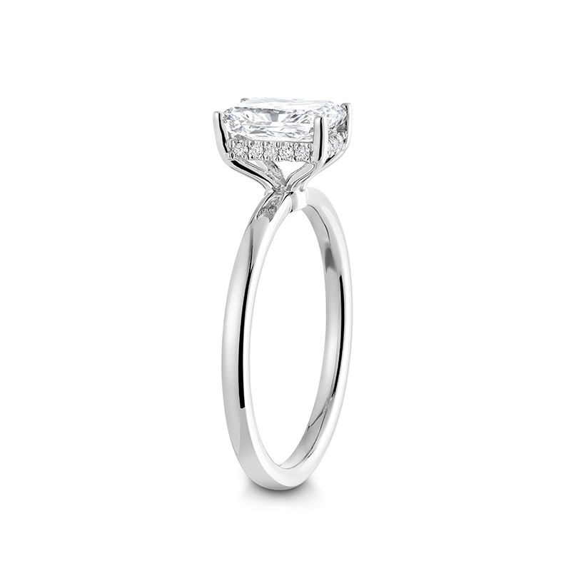 Stunning engagement ring in 18K white gold, featuring a 2ct radiant cut diamond, held high above a slim 1.8mm band with a hidden halo of small pavé diamonds.