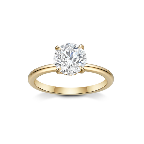 Charming engagement ring in 18K yellow gold, featuring a 1.5ct round brilliant diamond in an eagle claw setting, accented with a hidden halo of small diamonds.