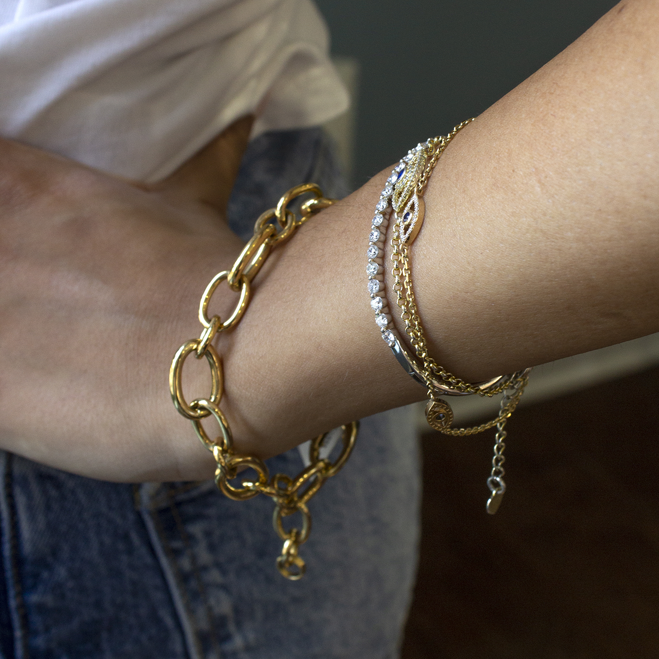 Model wearing an assortment of bracelets, including the Blaze Bangle and yellow gold chains.