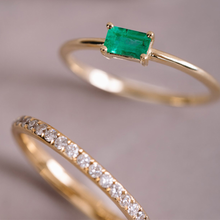 Load image into Gallery viewer, Elegant &#39;Emerald Burst&#39; ring in 14K yellow gold, featuring a 0.25ct baguette-cut emerald in a low and long claw setting, slim and vibrant, ideal for unique stacking arrangements.
