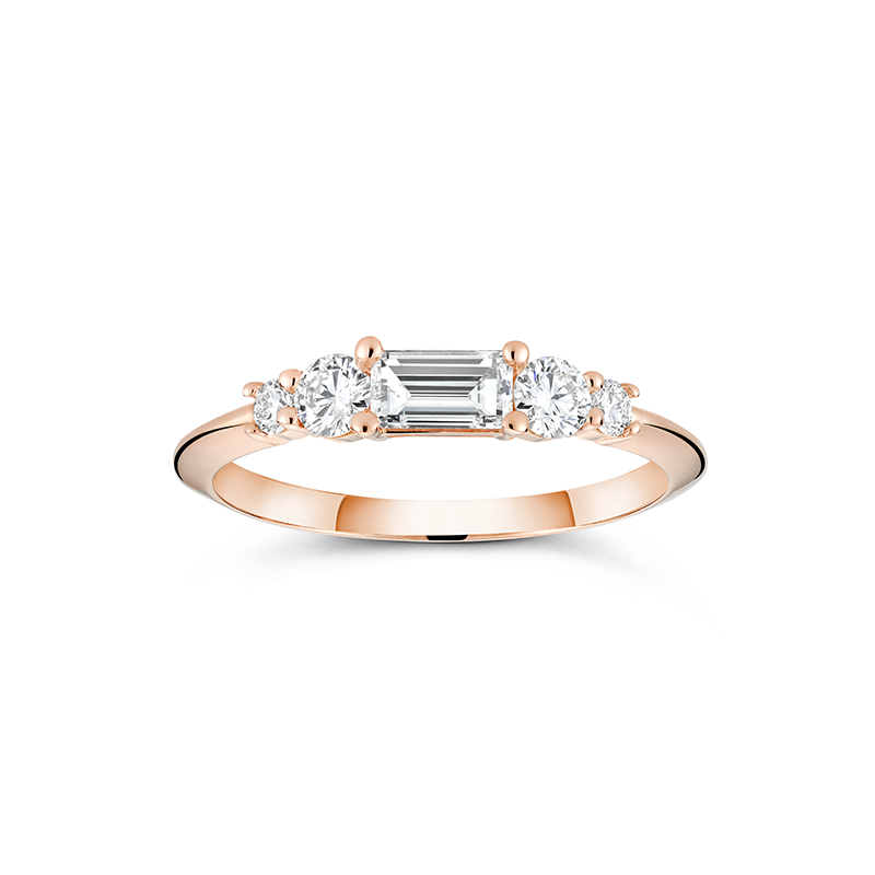 Rose gold engagement ring with a distinctive low knife-edged band, featuring a 0.31ct baguette cut diamond center, flanked by four round brilliant diamonds totaling 0.58tcw in prong settings, creating a scaffold-like structure.