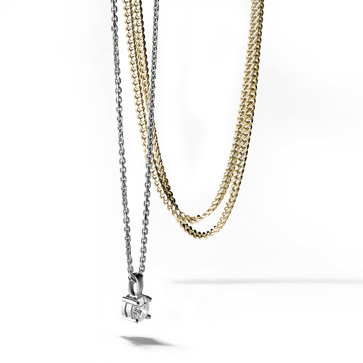 18K white gold pendant featuring a gracefully tapering bail and a claw-set round brilliant diamond of about .42ct, on a 17" chain, exemplifying classic elegance and handcrafted expertise by Ex Aurum in Montreal. Other yellow gold chain necklaces displayed in the background.