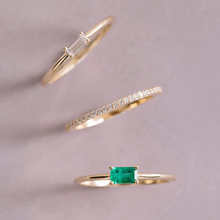 Load image into Gallery viewer, Emerald Burt ring with other stacking rings. 14K yellow gold, featuring a 0.25ct baguette-cut emerald in a low and long claw setting, slim and vibrant, ideal for unique stacking arrangements.
