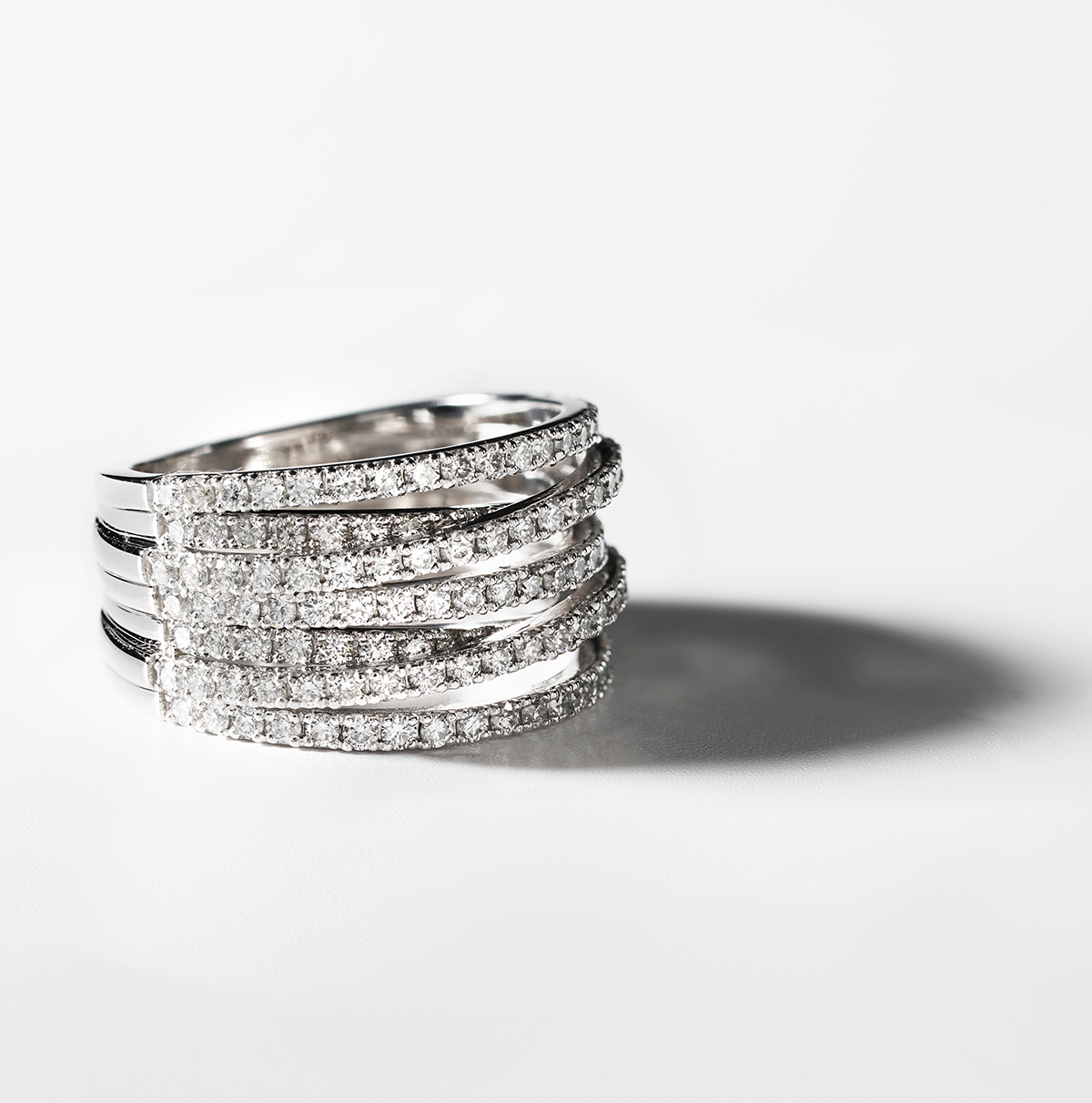 Ring in 14K white gold, a statement piece weighing approximately 9.80gr, adorned with 1.73tcw of round diamonds in a pavé setting, designed to mimic the graceful undulations of sparkling ribbons.